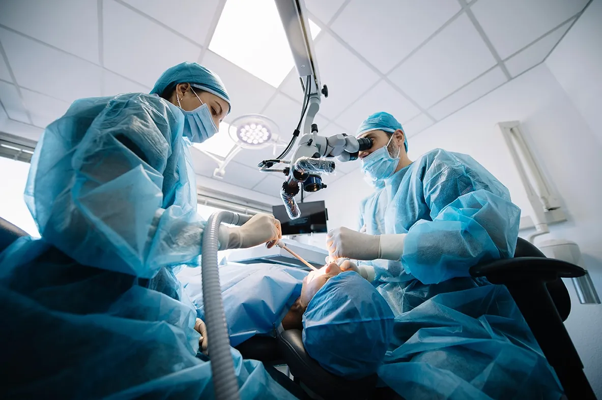 Équipe odontoiatrica al lavoro con il microscopio operatorio